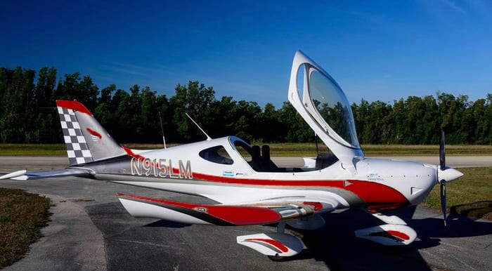 A small white and red plane sitting on top of an airport runway.