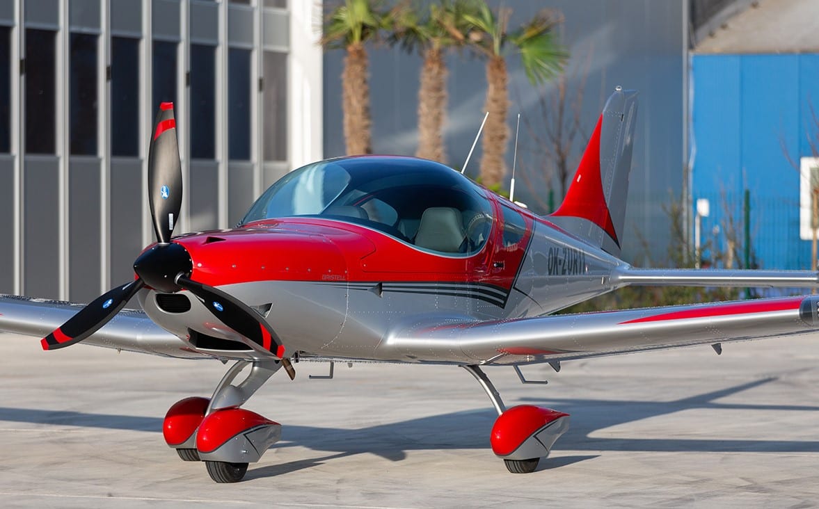 A small red and silver airplane parked on the concrete.