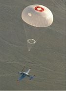 A parachute is flying in the sky above a boat.