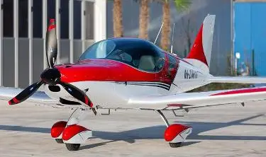 A red and white plane is parked on the street.
