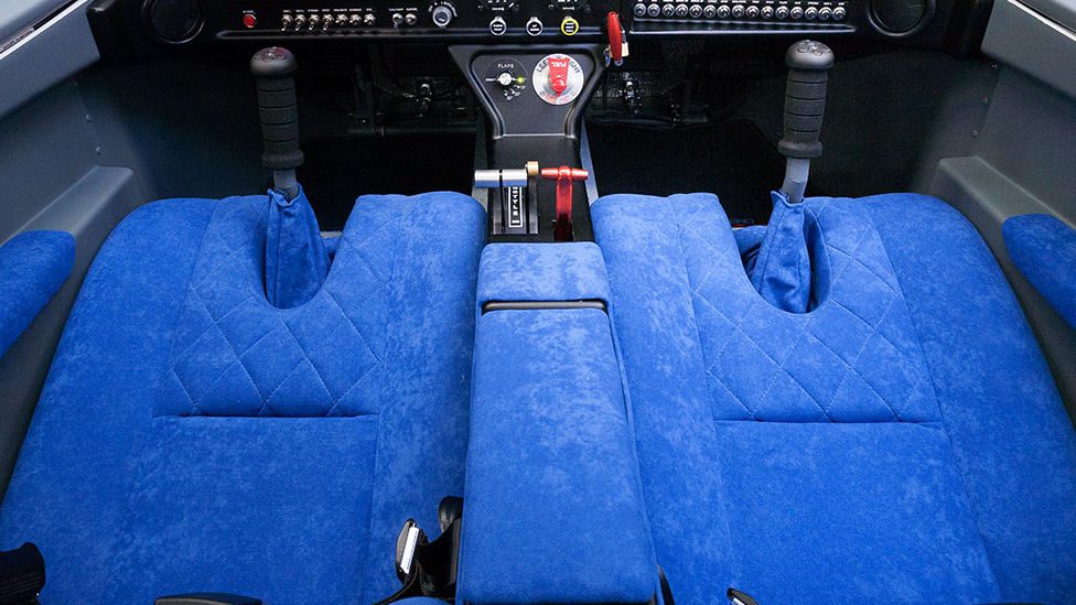 A blue seat in the back of an airplane.