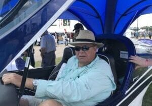 A man in a blue hat sitting inside of an open car.