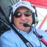 A man in a helicopter with headphones on.